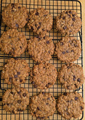 12 Peanut Butter flavored Oatmeal cookies with chocolate chips on a black cooling rack on a wooden surface. 